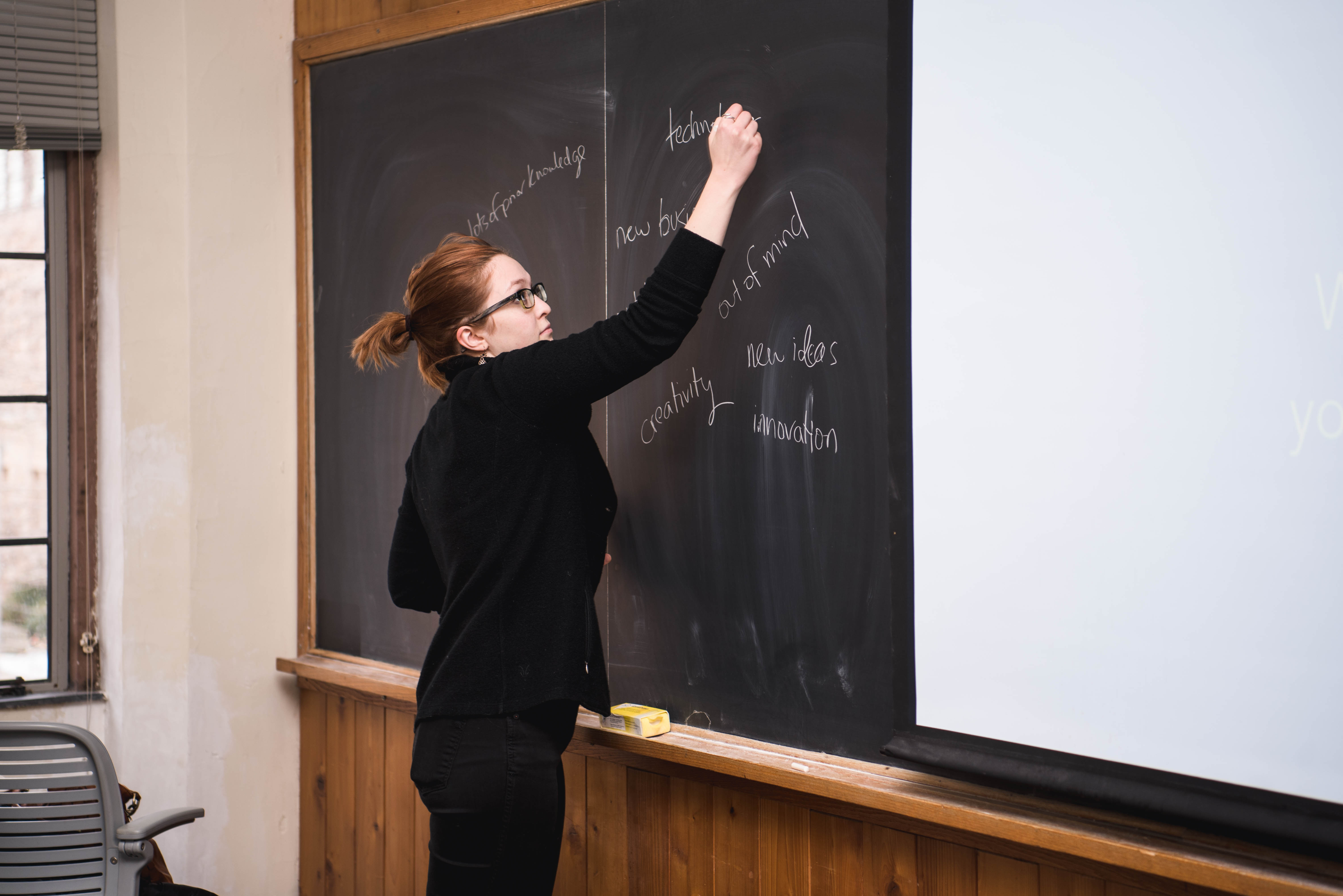 Instructor writes on chalkboard