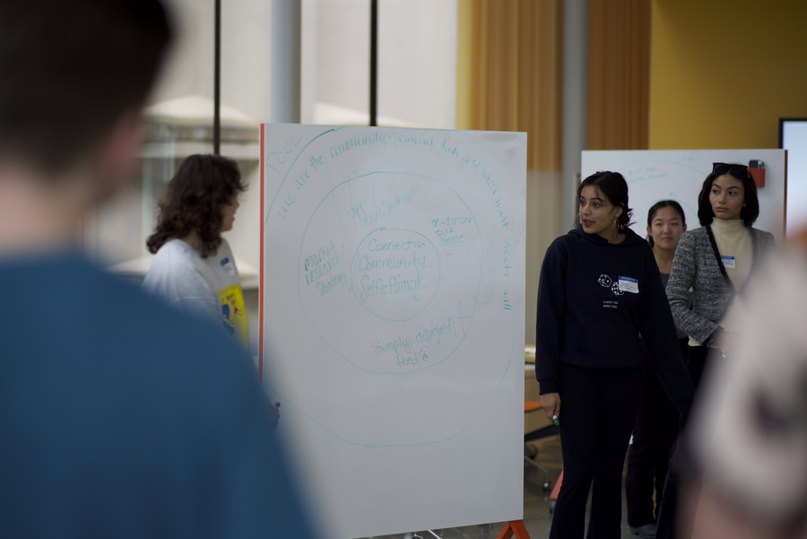 group of students discussing problem at a whiteboard