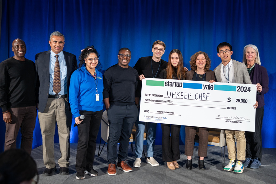 group of people standing on a stage holding a large check