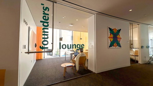 Relaxing lounge space in building with the words "founders' lounge" on the glass door