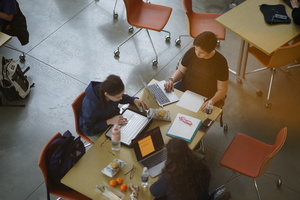 People sitting at tables with laptops, working together.