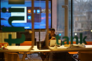 A man sitting at a table with a laptop computer, working on a project.