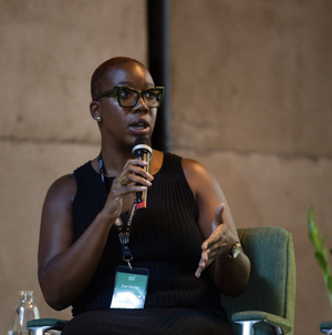 black woman speaking into a microphone on stage in front of a crowd