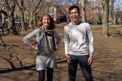 woman and man smiling and standing outside in the park.