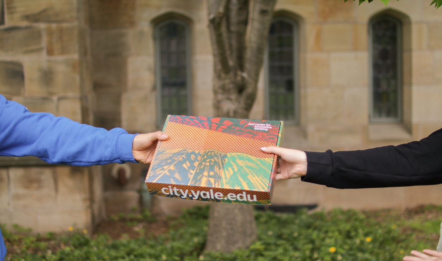 Hands pass Tsai CITY-branded box on Yale campus