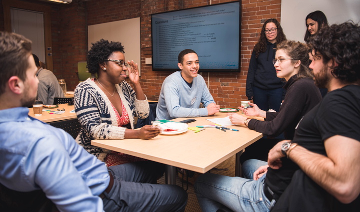 Group of students talk around table