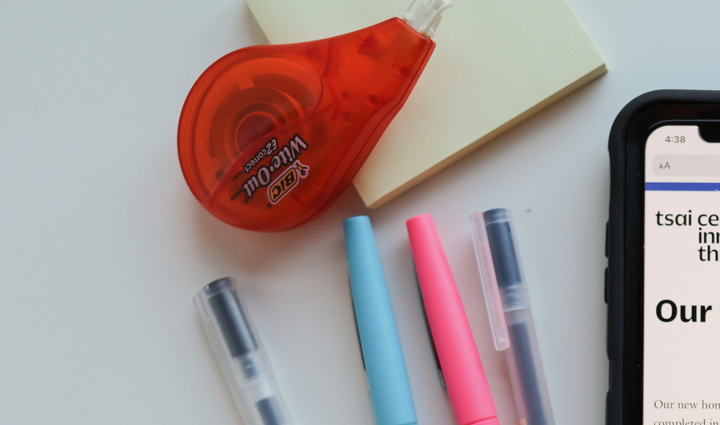 Flatlay image of desk supplies and Tsai CITY website on smartphone