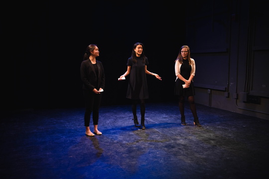 Three students speak on stage