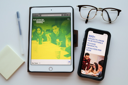 Flatlay image of desk supplies and Tsai CITY imagery on mobile devices