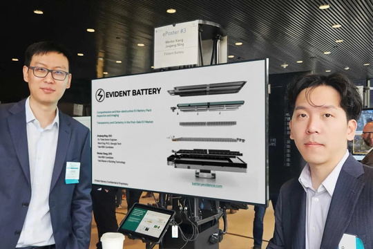 Two men standing next to a large screen, presenting their venture EVident Battery.