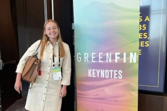 woman standing in front of a pop-up banner with the text GreenFin Keynotes