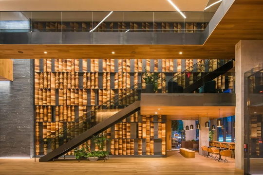 Modern interior with a wooden staircase, illuminated wood paneling, and a glass railing by Cambium Carbon.