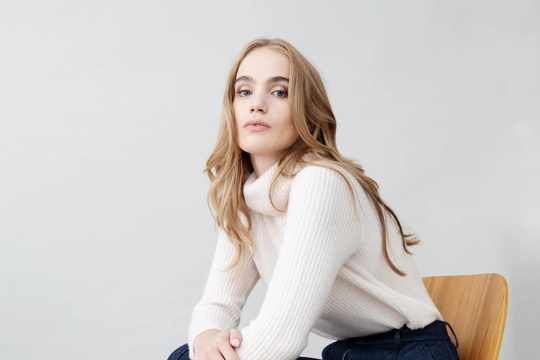 girl sitting in a chair with tailored pants and a sweater 